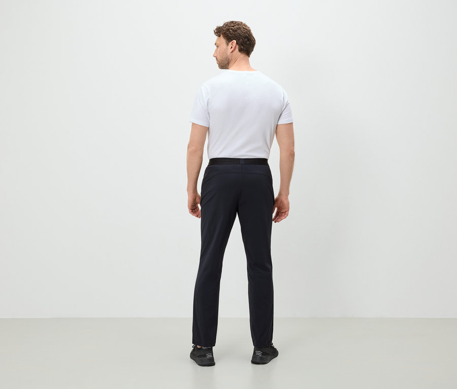 Muž chrbtom k fotoaparátu má na sebe biele tričko, čierne nohavice a čierne topánky.