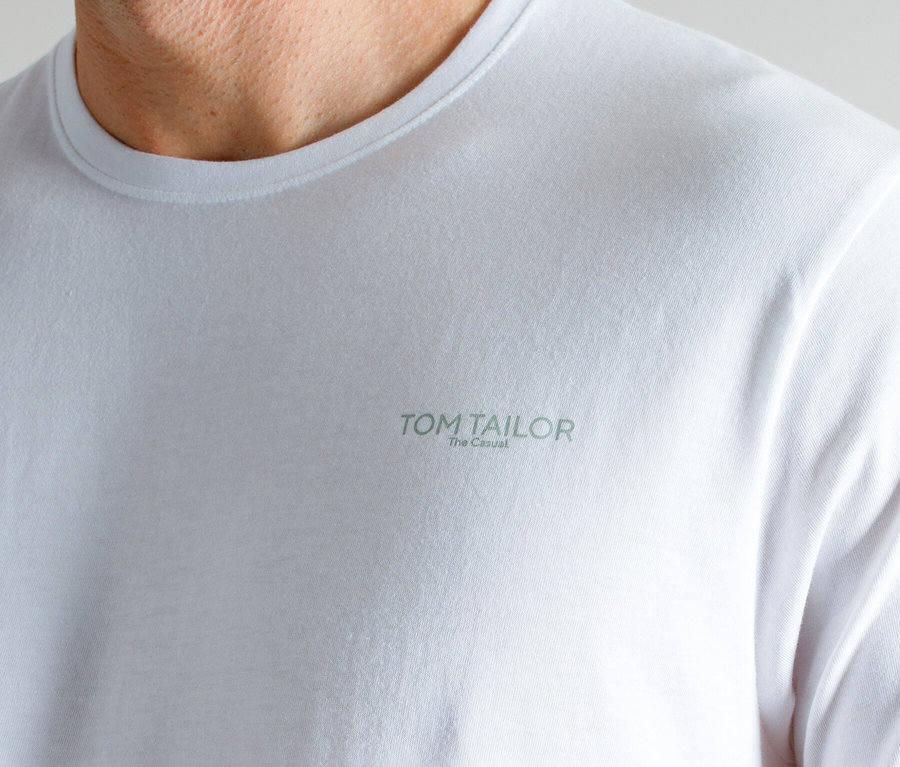Detailný záber na krk a ramená muža v bielom tričku s potlačou TOM TAILOR The Casual.