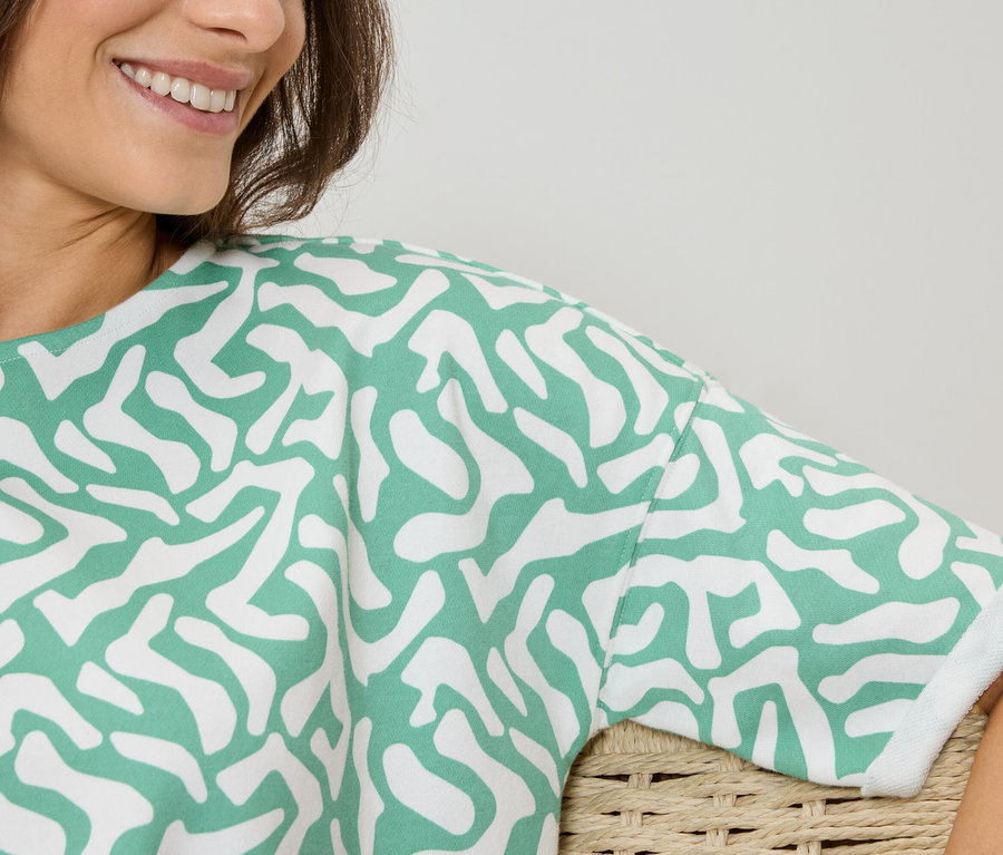 Žena má na sebe top so zeleno-bielym vzorom.