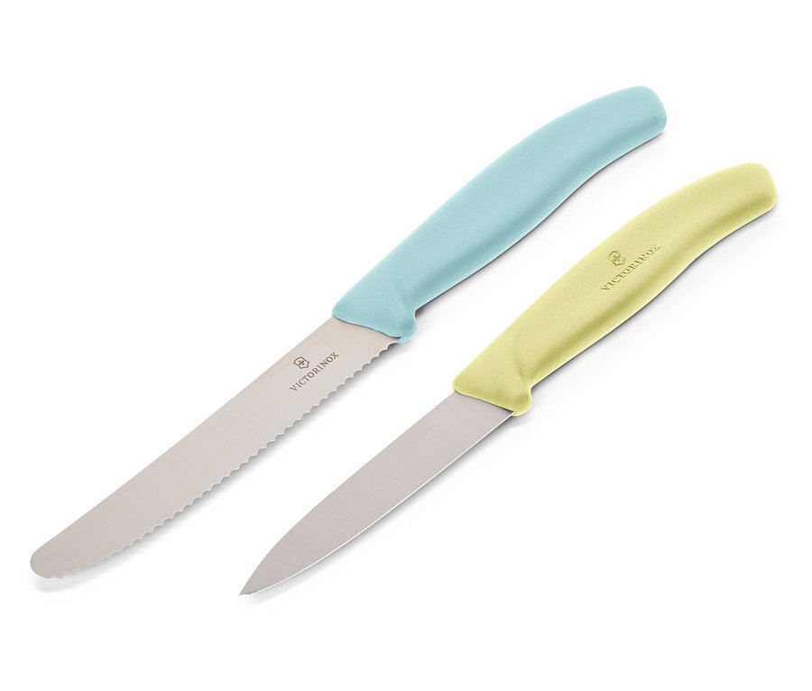 Dva nože Victorinox ležia diagonálne na bielom pozadí. Horný nôž má svetlomodrú rukoväť a zúbkovanú čepeľ, dolný nôž má svetložltú rukoväť a hladkú čepeľ.