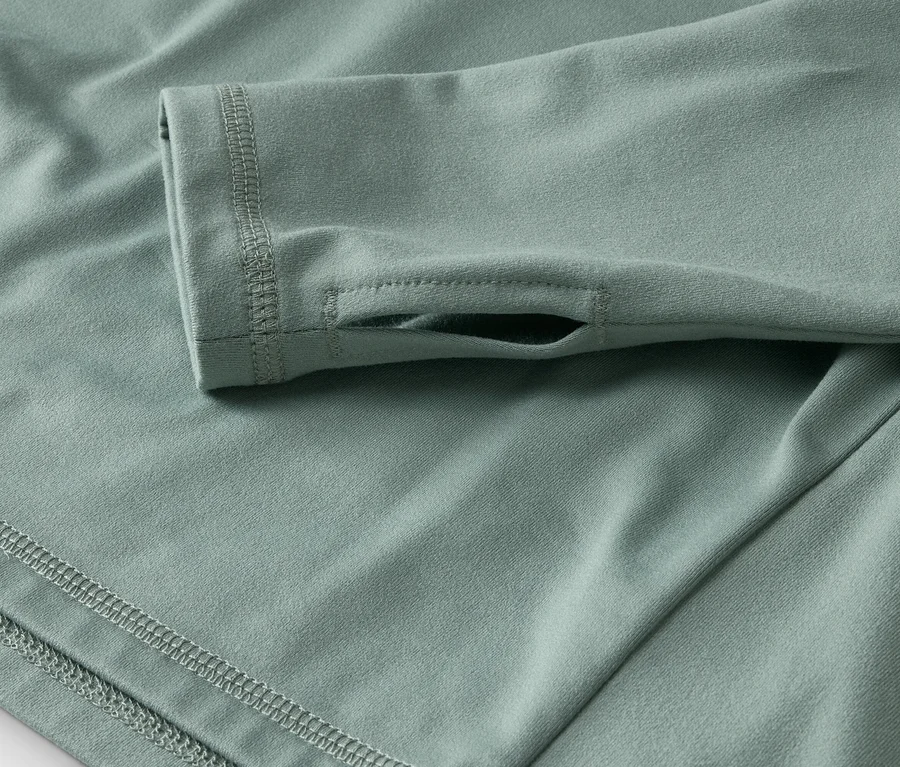 Detailný záber svetlozeleného trička s dlhým rukávom a otvorom na palec.