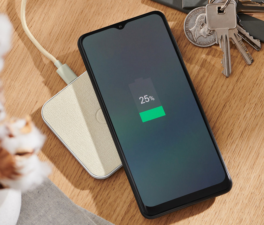 Mobilný telefón sa nabíja na sivej bezdrôtovej nabíjacej stanici.