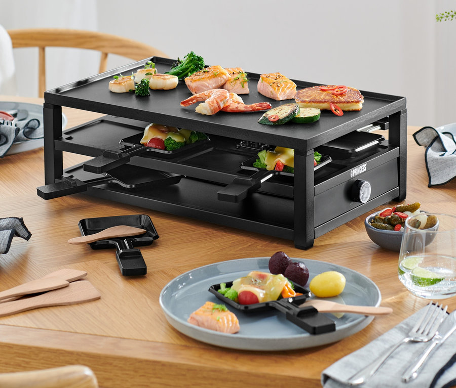 Raclette pre 8 osôb na stole s jedlom na tanieroch.