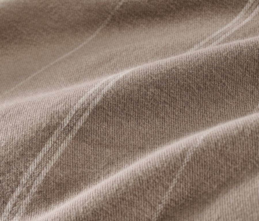 Detail hnedosivej flanelovej posteľnej bielizne.