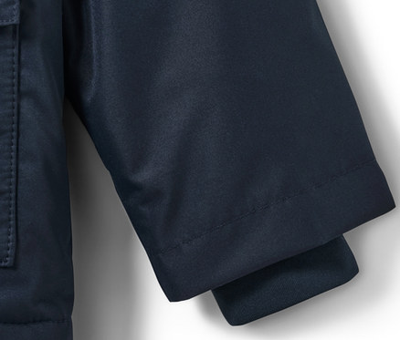 Detail detskej termo bundy do dažďa s motívom psa, zobrazujúci rukáv a vrecko.