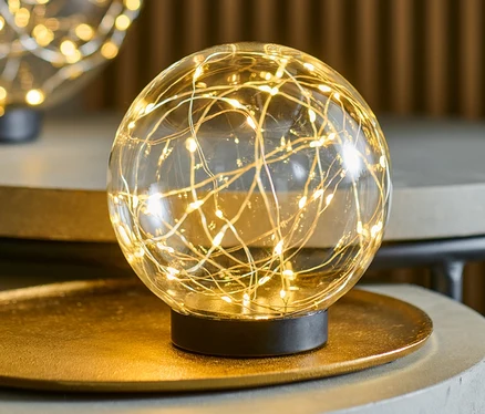 Dve sklenené gule s LED svetielkami, každá s priemerom cca 15 cm, stoja na sivých stolíkoch.