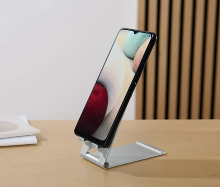 Čierny smartfón stojí na Stojane na smartfón a tablet na stole.