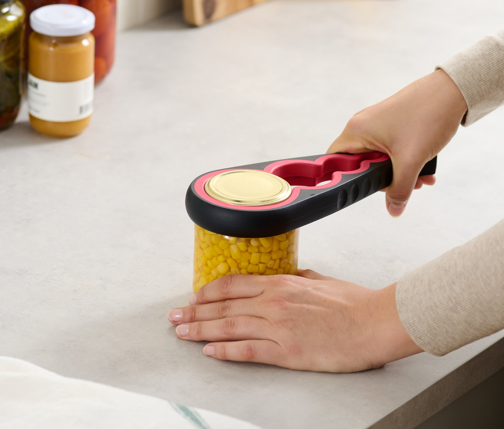 Žena otvára pohár kukurice pomocou otvárača na poháre a fľaše.