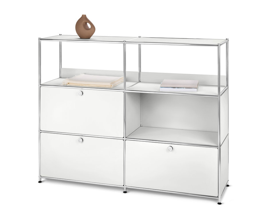 Biela kovová komoda »CN3« s 2 výklopnými dvierkami a 1 zásuvkou. Hore leží hnedá váza a poskladané oblečenie.
