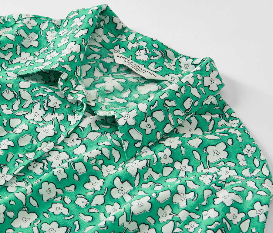 Detail zelených košeľových šiat s bielou kvetinovou potlačou.