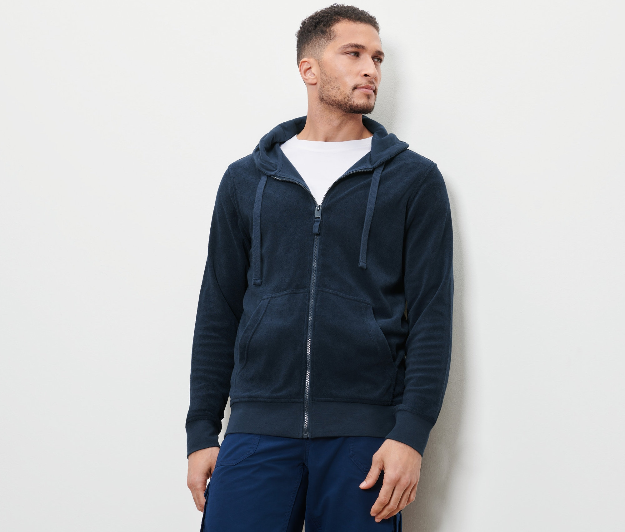 Muž má na sebe modrú froté bundu s kapucňou.