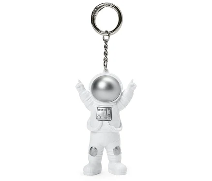 Biely prívesok na kľúče v tvare astronauta s natiahnutými rukami.