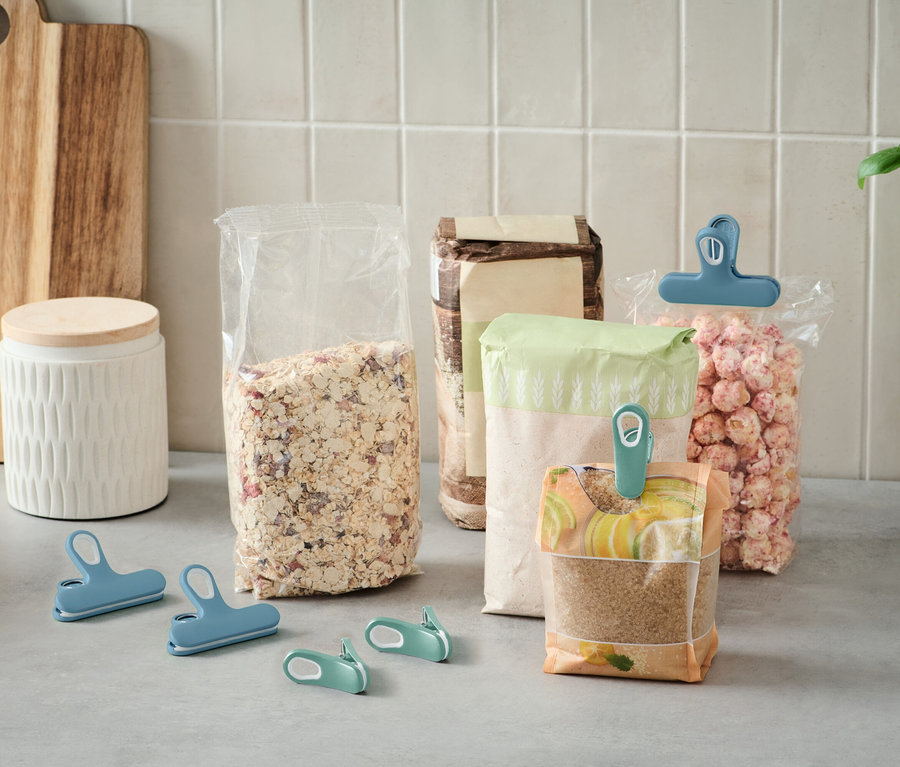 Na linke stojí niekoľko otvorených vrecúšok s jedlom, ktoré sú uzavreté farebnými klipmi.