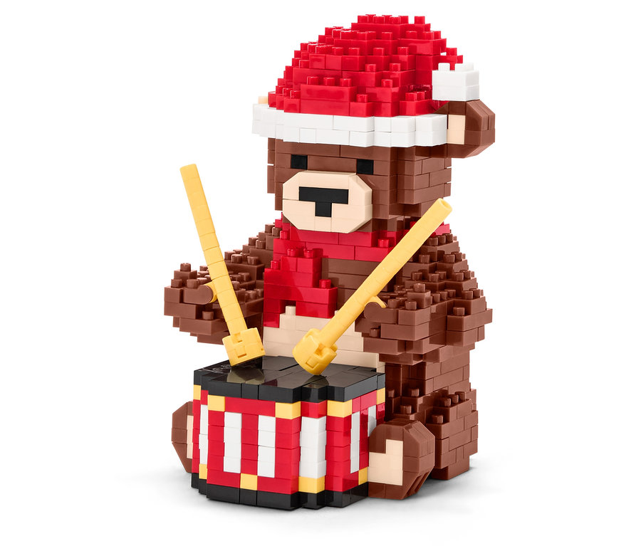 Hnedý medvedík z kociek s červenou čiapkou a šálom hrá na bubon s paličkami.