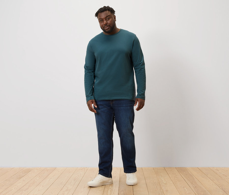 Muž stojí a má na sebe džínsy a zelené tričká s dlhými rukávmi, 2 ks.