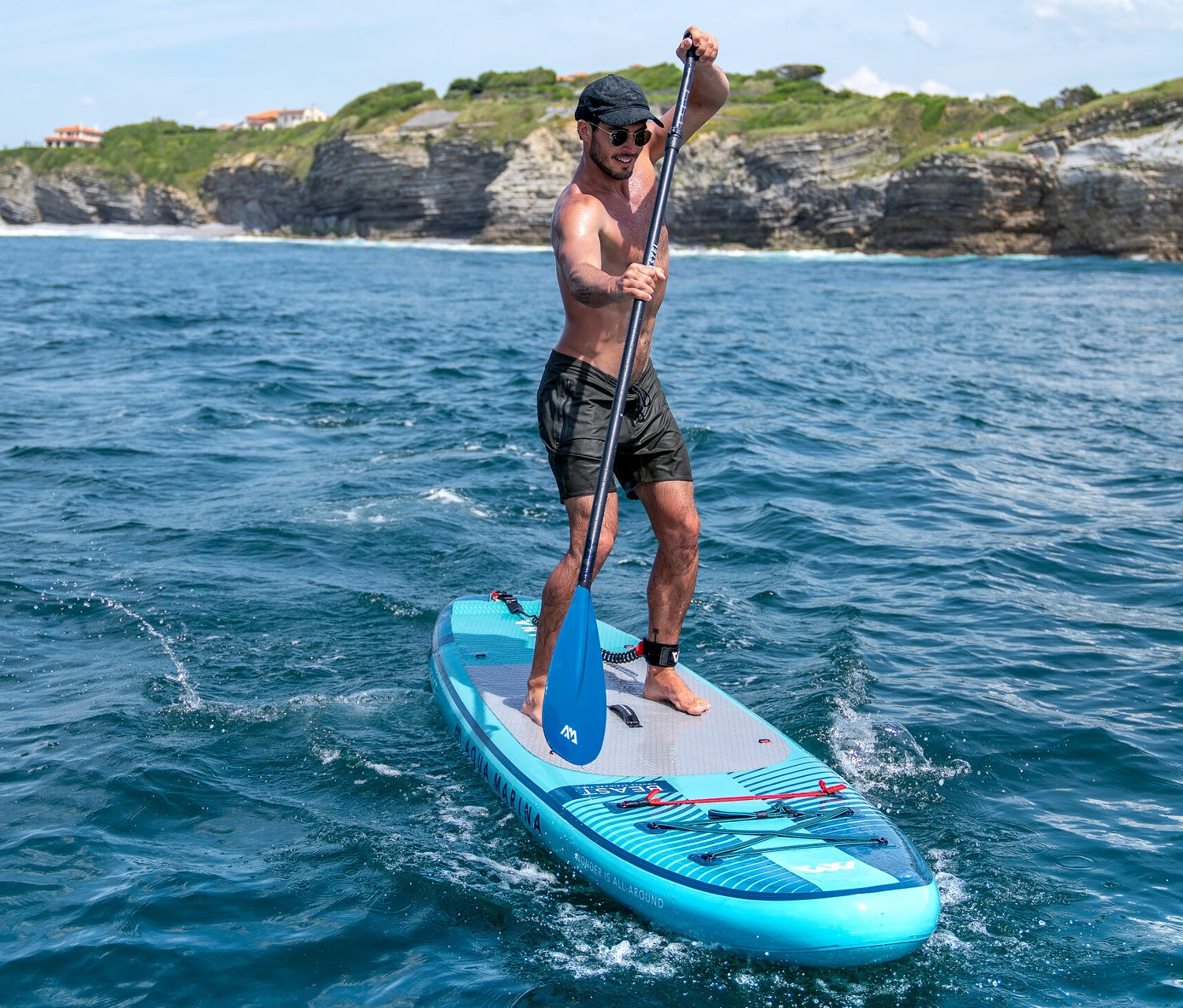 Muž vesluje na modrom paddleboarde Aqua Marina »Beast« 10'6" na mori.