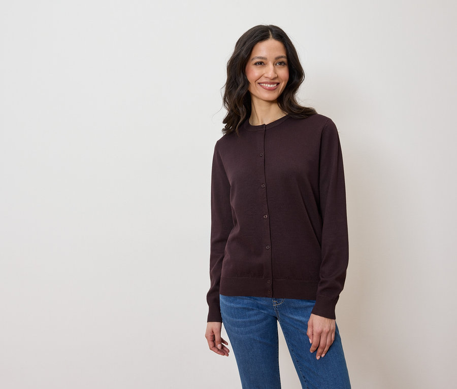 Žena má na sebe tmavofialový kardigán a džínsy.