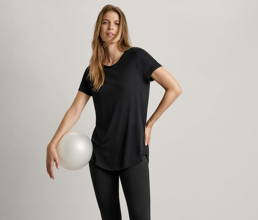 Žena drží loptu a má na sebe čierne dlhé tričko.