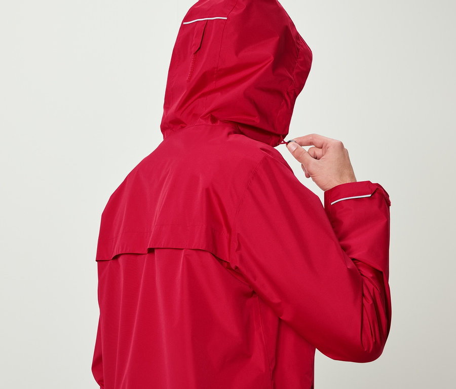 Muž v červenej bunde si upravuje kapucňu.