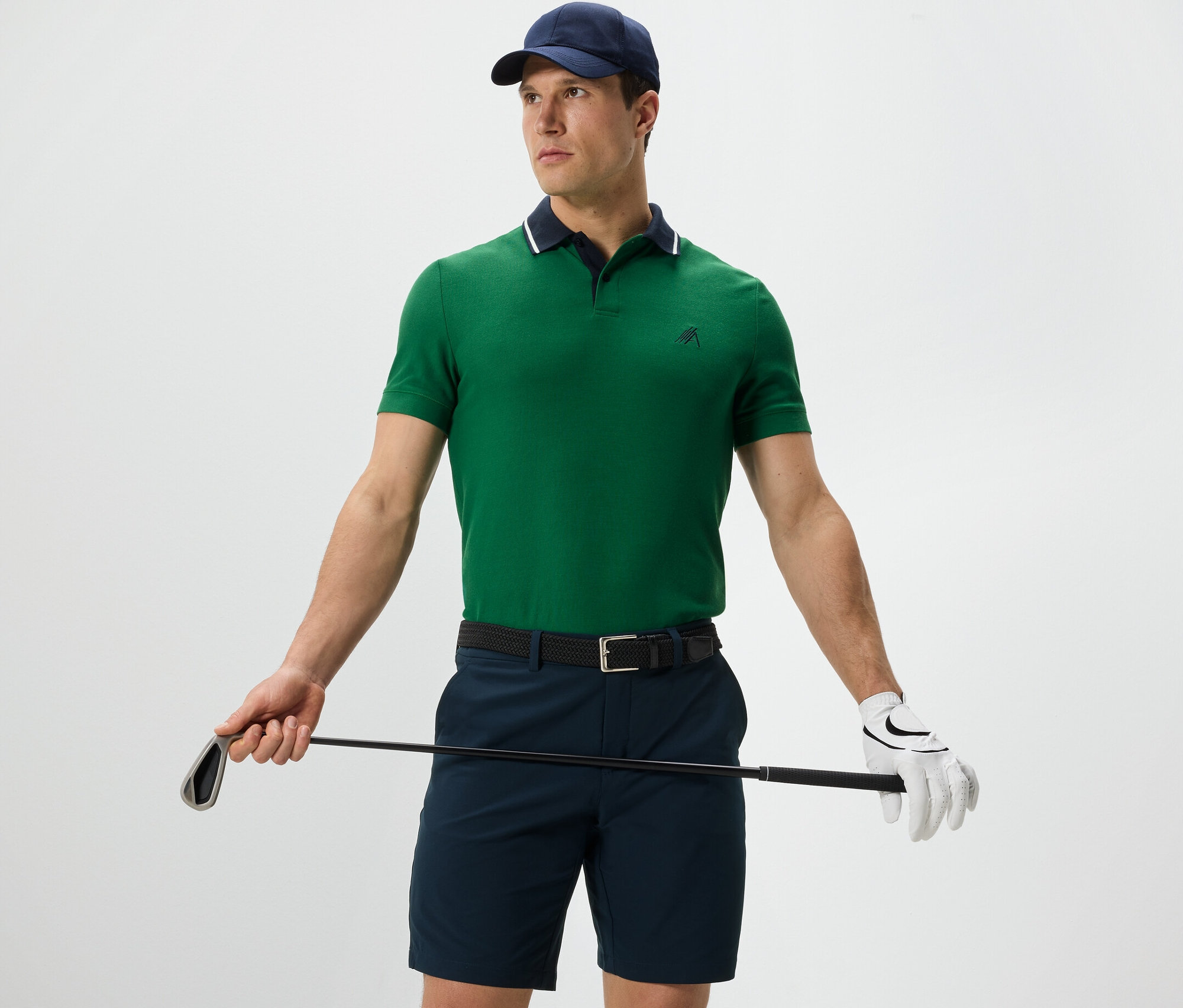 Muž drží golfovú palicu a má na sebe zelenú funkčnú polokošeľu.