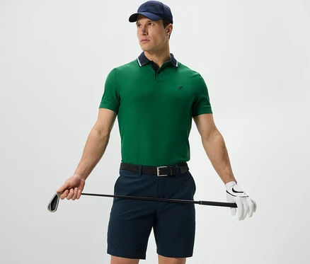 Muž drží golfovú palicu a má na sebe zelenú funkčnú polokošeľu.