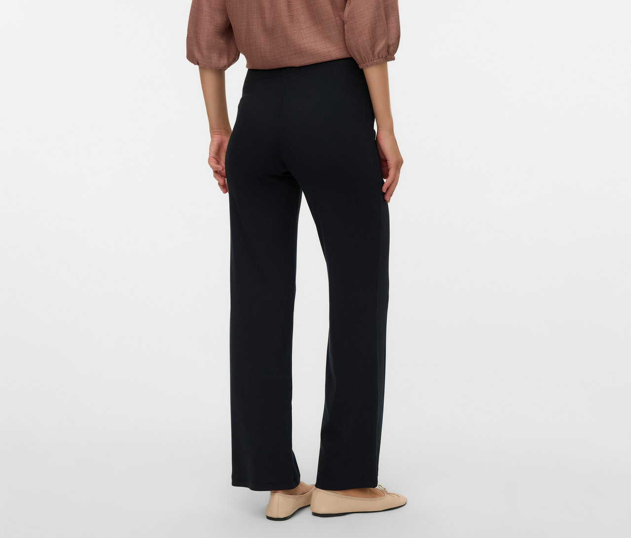 Pohľad zozadu na ženu v hnedej blúzke a čiernych voľných legínach MAMALICIOUS »MLEMILY« a béžových balerínkach.