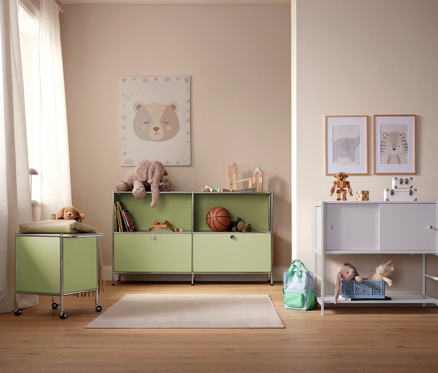 Detská izba so svetlozelenými a bielymi úložnými skrinkami, hračkami a obrázkami na stene.