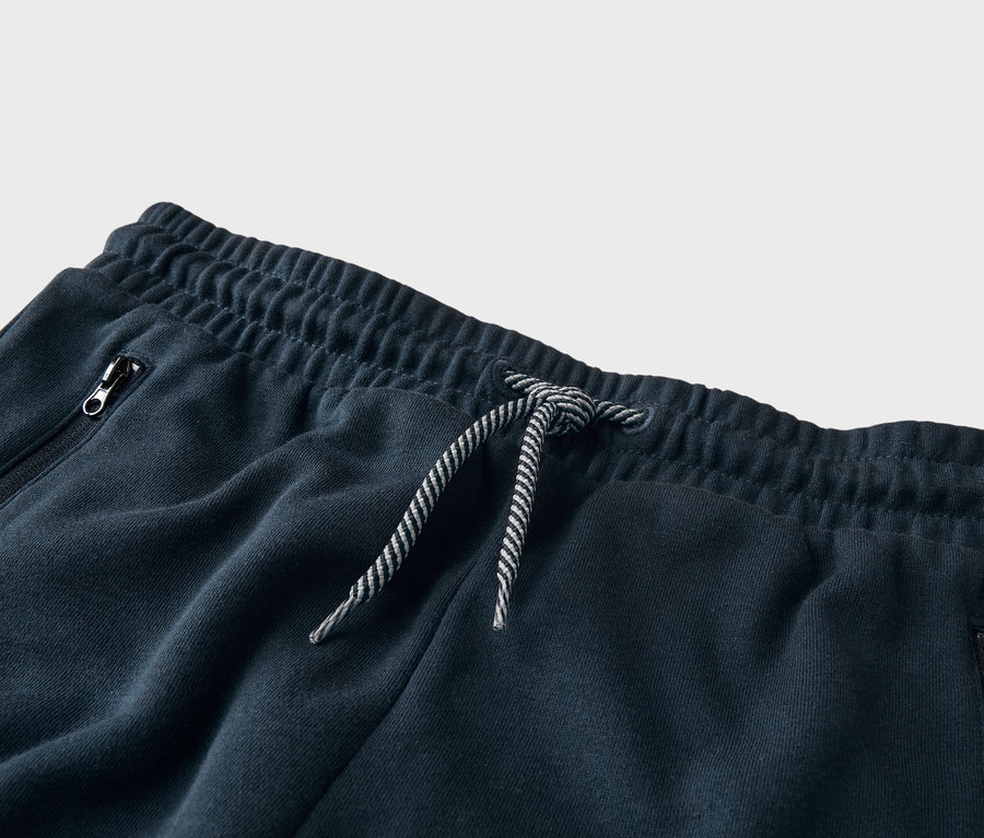 Detailný záber na tmavomodré tepláky so šnúrkou a vreckom na zips.