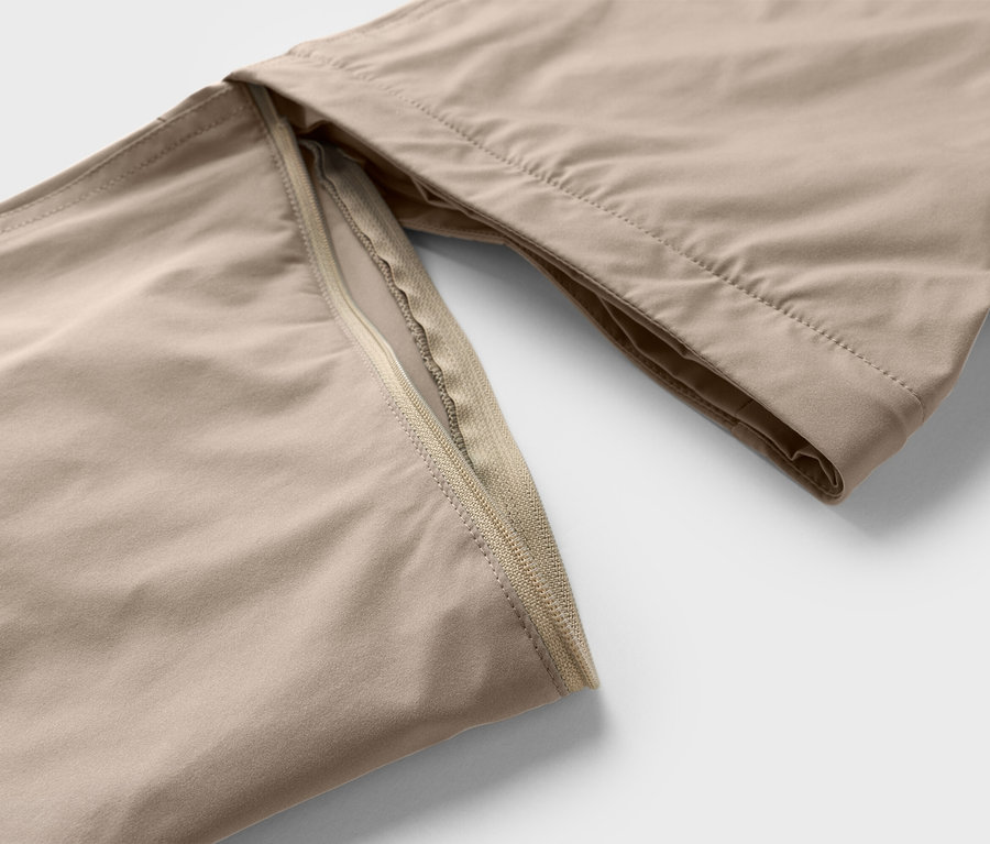 Detailný záber béžových nohavíc so zipsom.