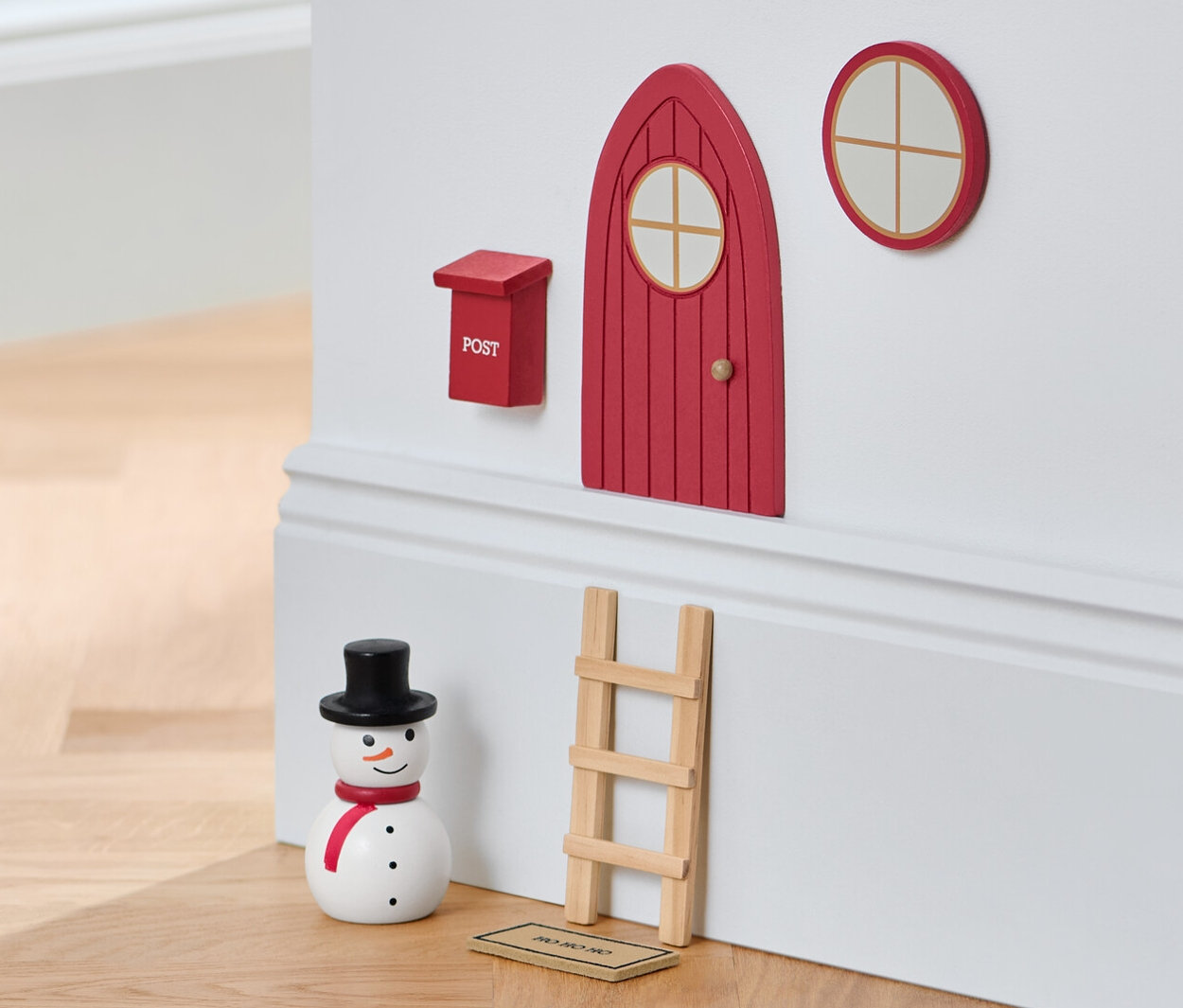 Súprava miniatúrneho nábytku na stene vedľa snehuliaka a stoličky.