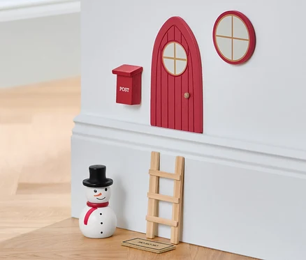 Súprava miniatúrneho nábytku na stene vedľa snehuliaka a stoličky.