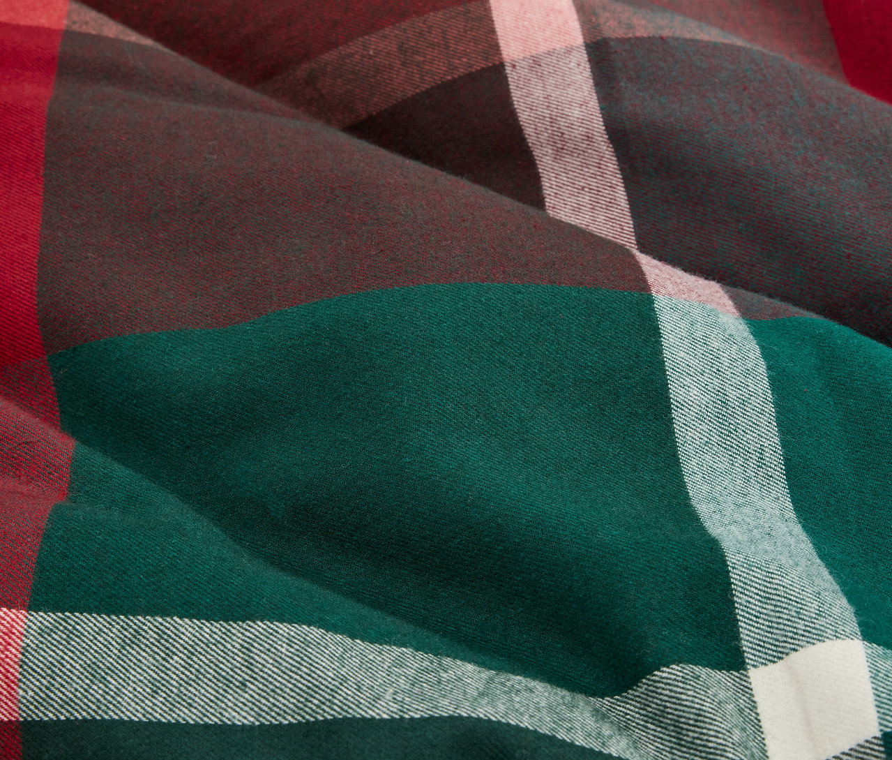 Detailný záber na látku s kockovaným vzorom v zelenej, hnedej, červenej a bielej farbe.