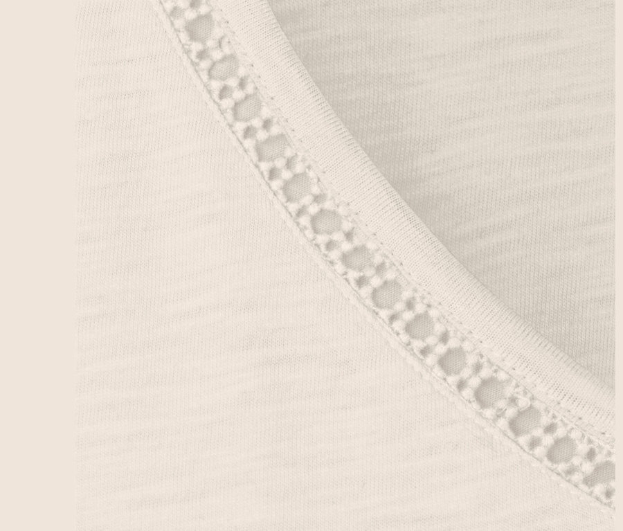 Detail krémovo-bieleho trička zo zmesi modalu s čipkovaným lemom.