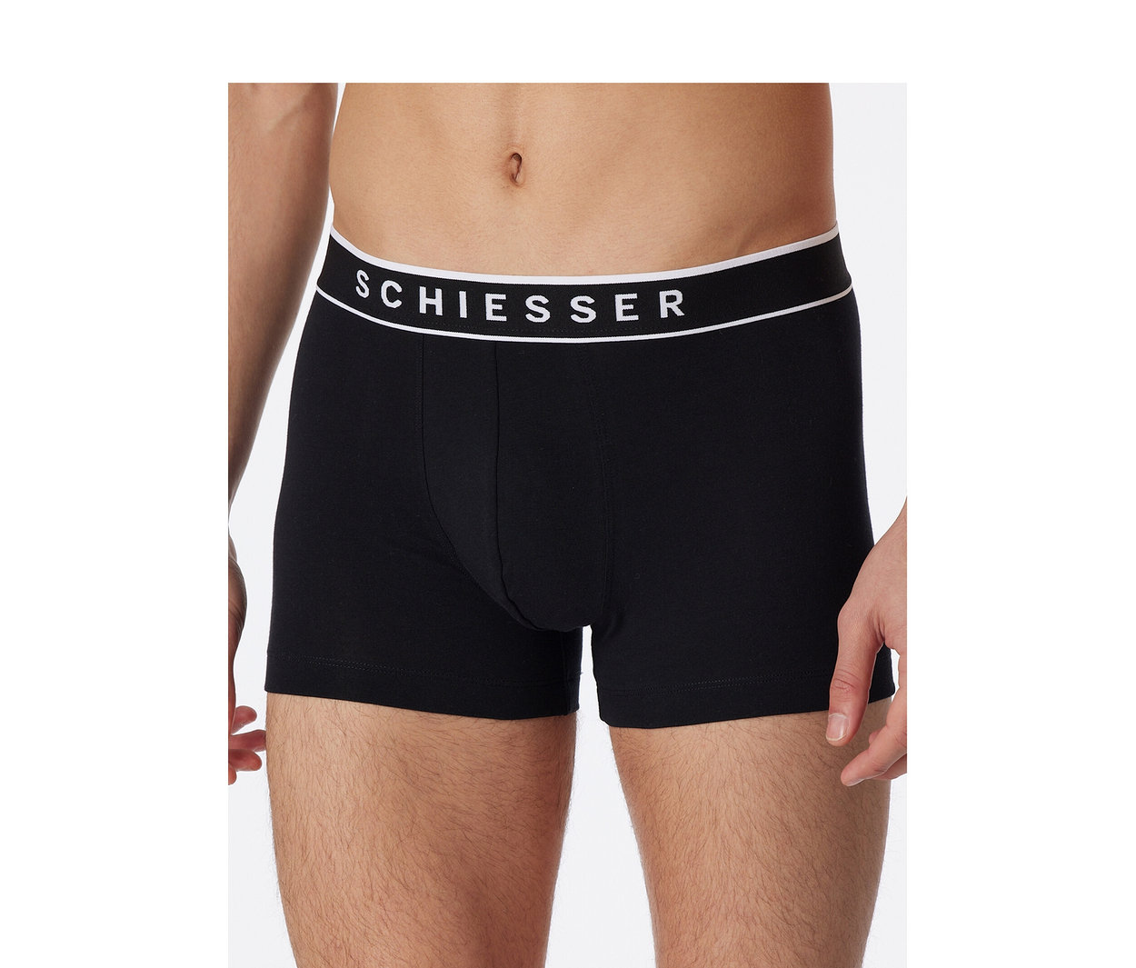 Muž v čiernych boxerkách SCHIESSER s bielym pásom s logom značky.