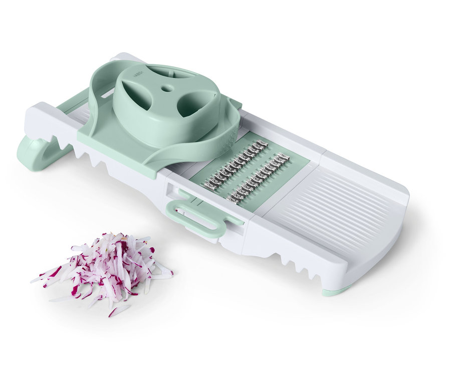 Biely krájač zeleniny so svetlozelenými akcentmi vedľa nakrájanej červenej cibule.