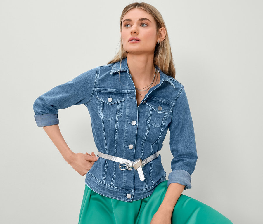 Blondínka pózuje v džínsovej bunde a saténovej sukni.