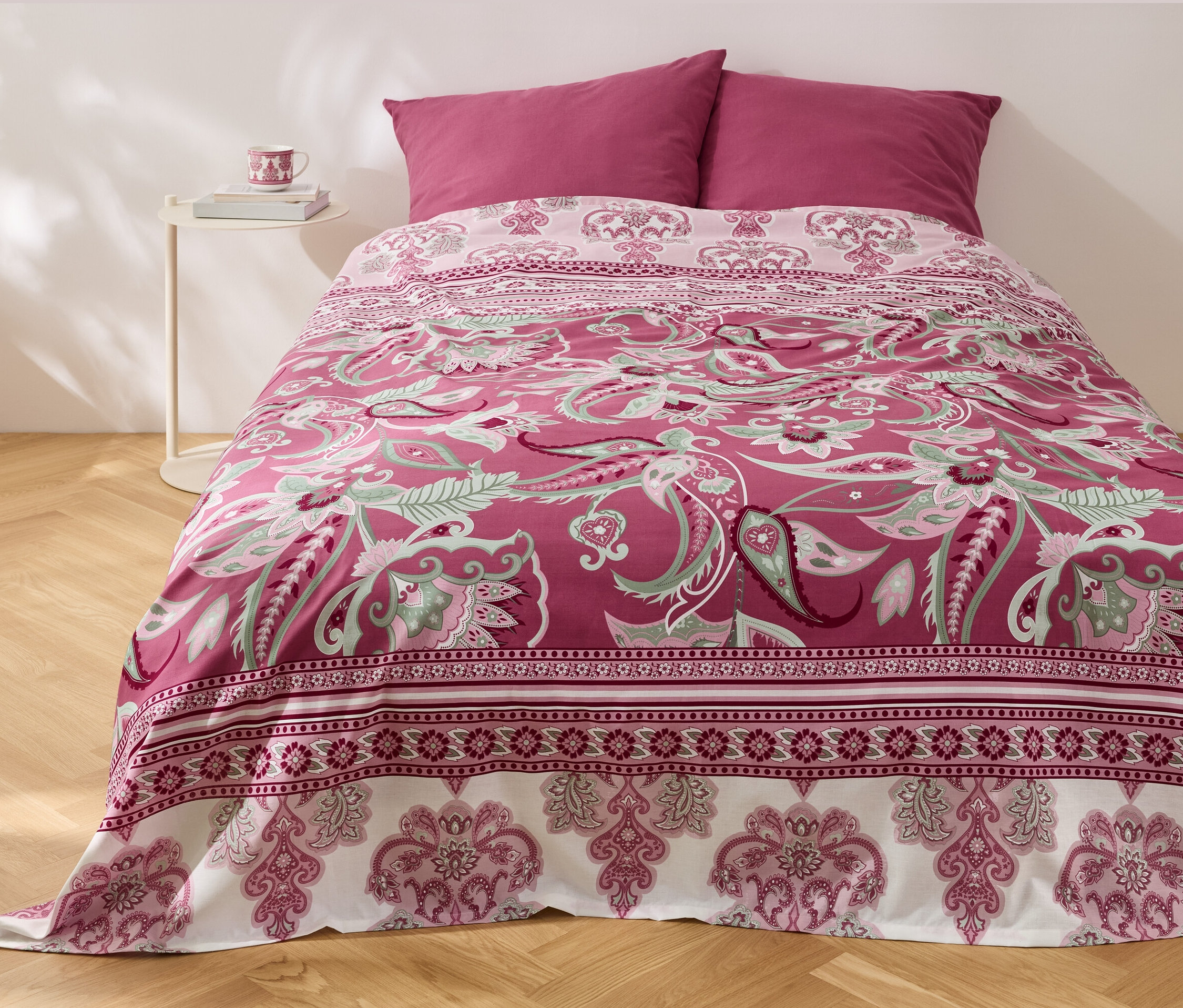 Posteľ s multifunkčným prehozom Renforcé s kvetinovým vzorom a dvoma vankúšmi.