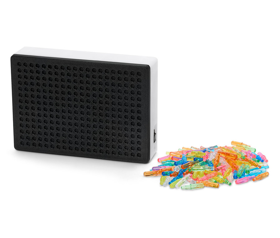 Čierna svetelná tabuľa s bielym rámom vedľa kopy farebných kolíčkov.