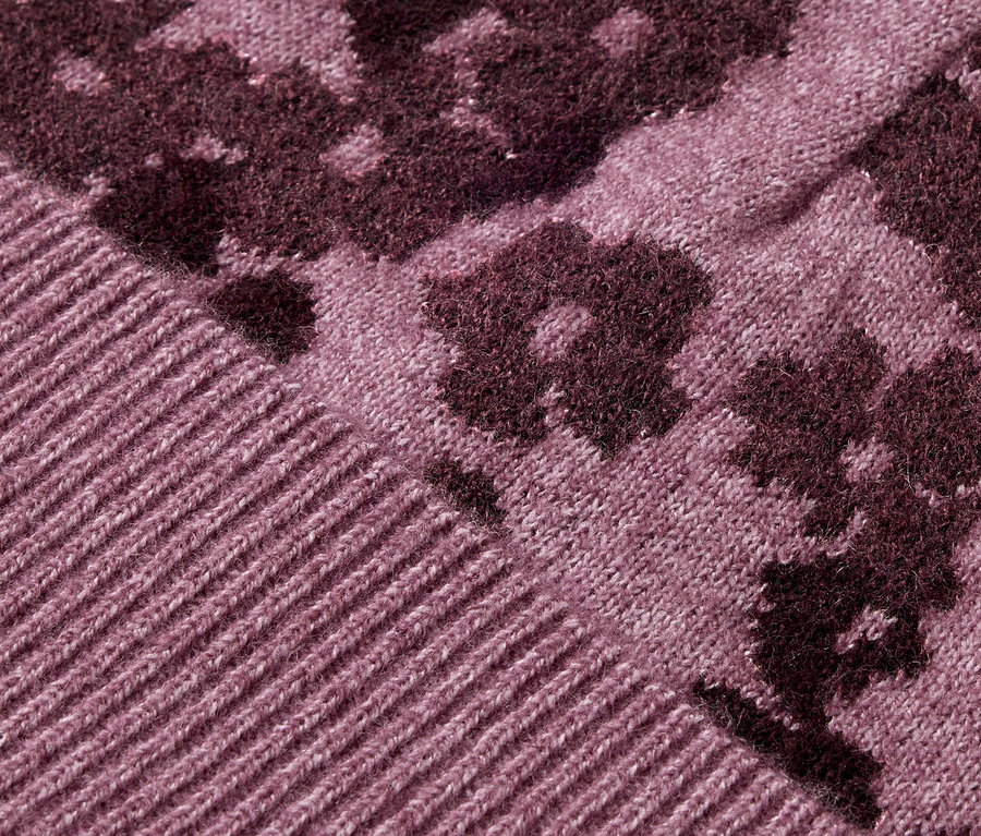 Detail fialového pleteného svetra s kvetinovým vzorom.