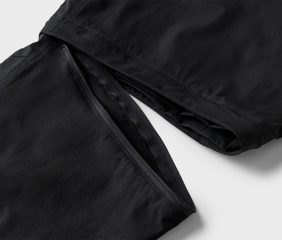 Detailný pohľad na čierne nohavice s otvoreným zipsom.