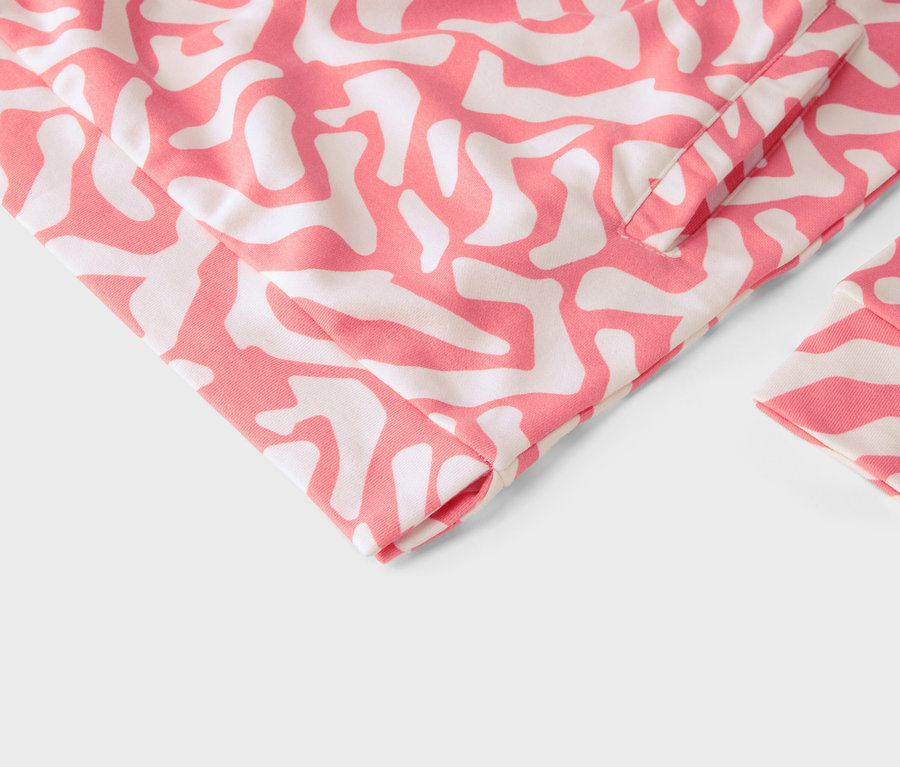 Detail odevu s ružovým a bielym abstraktným vzorom.