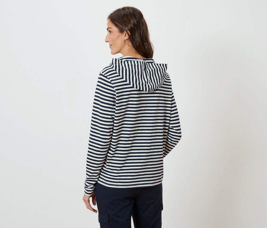 Žena zozadu, má na sebe pruhovanú mikinu s kapucňou a tmavomodré nohavice.