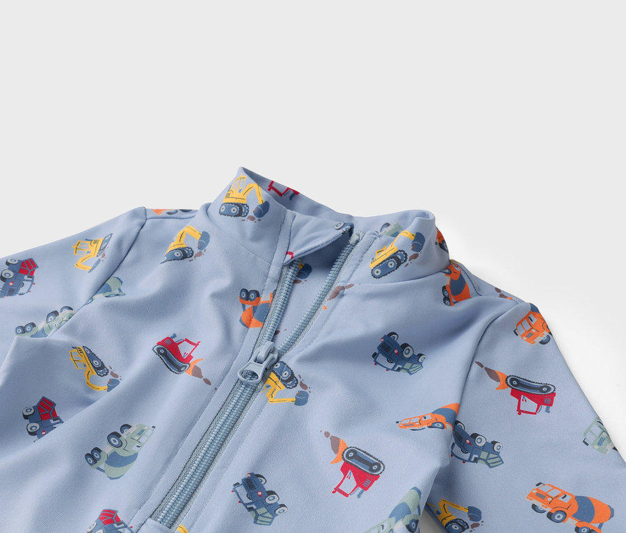 Svetlomodrá látka so zipsom a farebnými motívmi stavebných vozidiel.