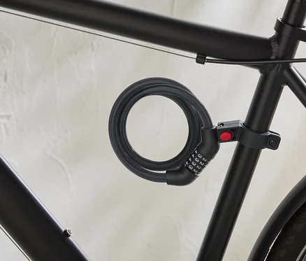Čierny bicykel má na ráme pripevnený špirálový káblový zámok s číselným kódom.