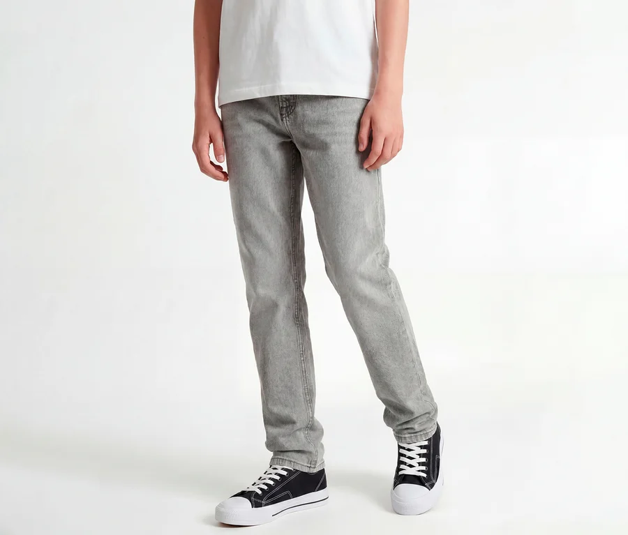 Stojaca osoba v bielom tričku, sivých džínsoch Jack&Jones JJOriginal Chris a čiernych teniskách.