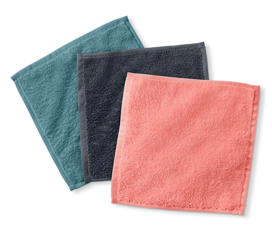 Tri kozmetické uteráky z mikrovlákna v odtieňoch modrej, šedej a koralovej farby ležia na bielom pozadí.