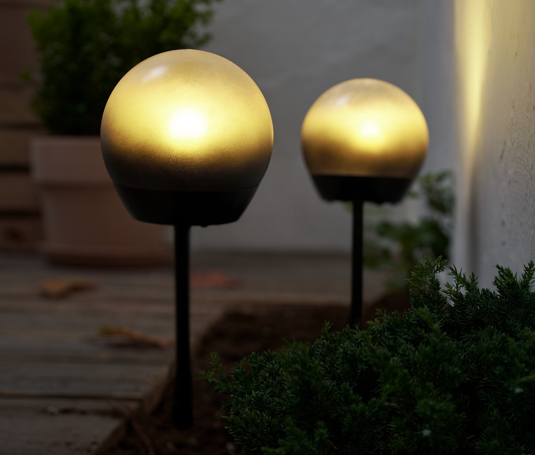 Dve guľové LED svietidlá osvetľujú zem vonku.