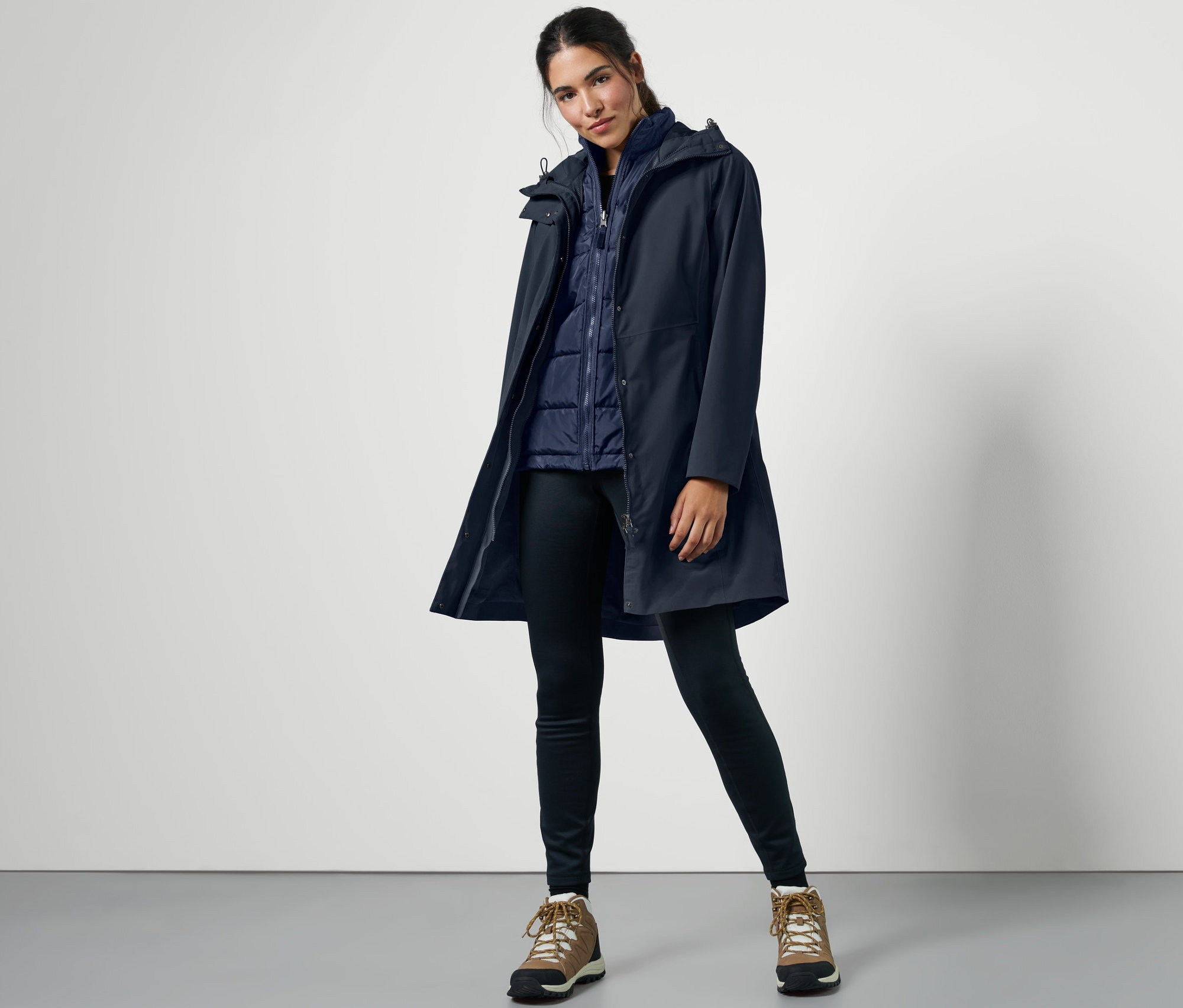 Žena pózuje v modrom outdoorovom kabáte 3 v 1 s vestou.