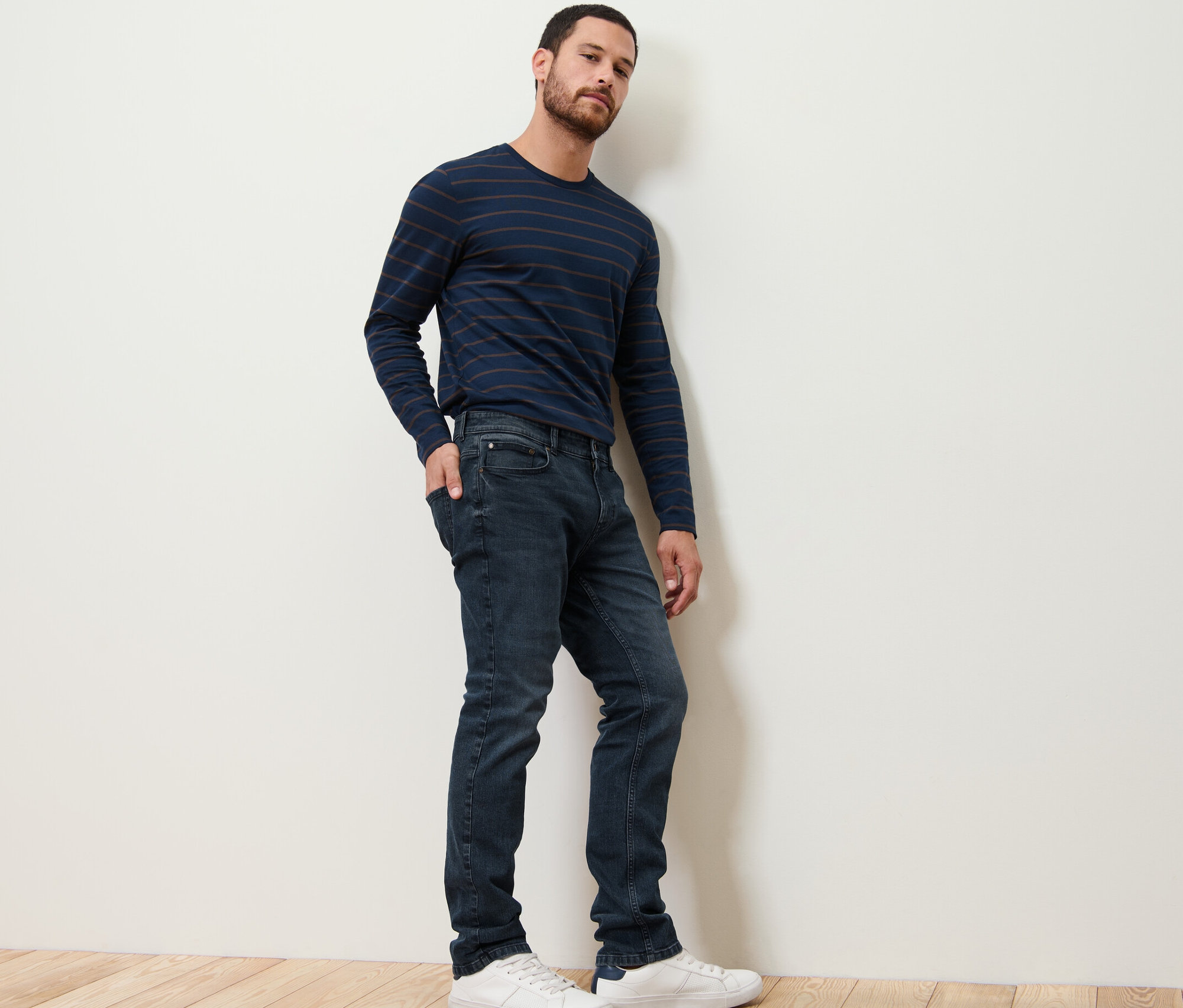 Muž pózuje v džínsoch a pruhovanom tričku.