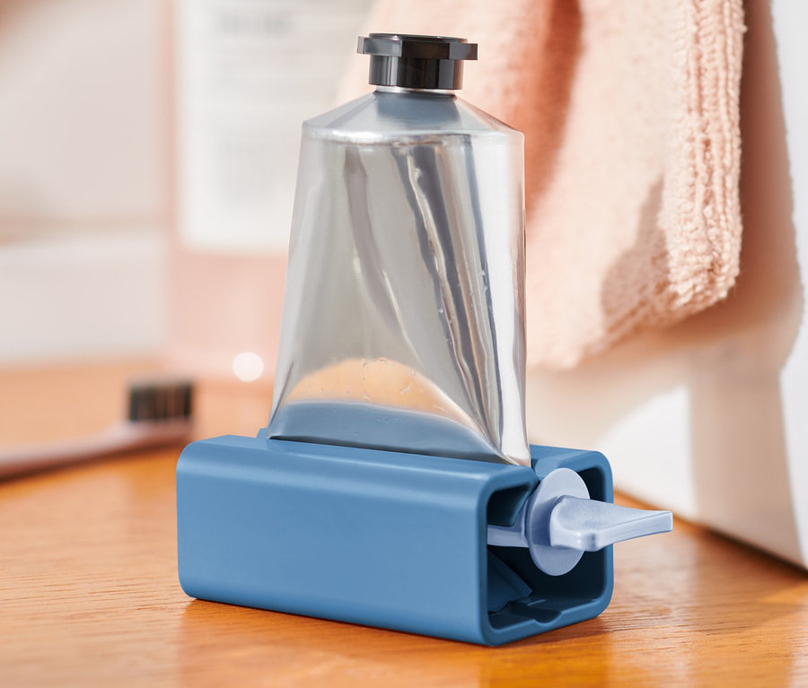 Strieborná tuba v modrej pomôcke na vytláčanie túb na drevenom stole.